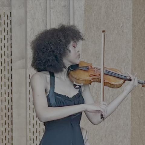 Woman in black gown and red heels playing violin in concert