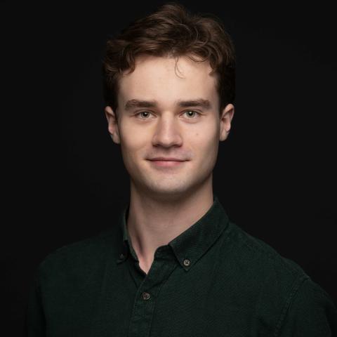 Headshot of man with slight smile against black backdrop