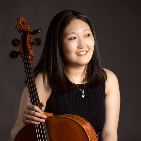 Woman holding cello and smiling off to the side