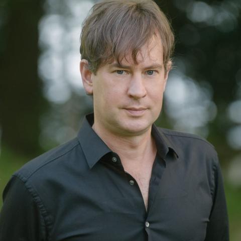 Taras Grescoe wearing a black shirt against a blurred background of trees