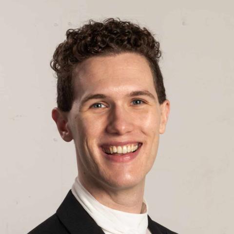 Man in performance attire smiling broadly at camera