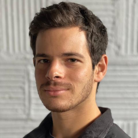Headshot of man with short hair smiling at camera wearing a black jacket